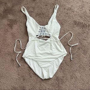 BECCA white one piece with wrap tie waist and shell detail. Adjustable straps